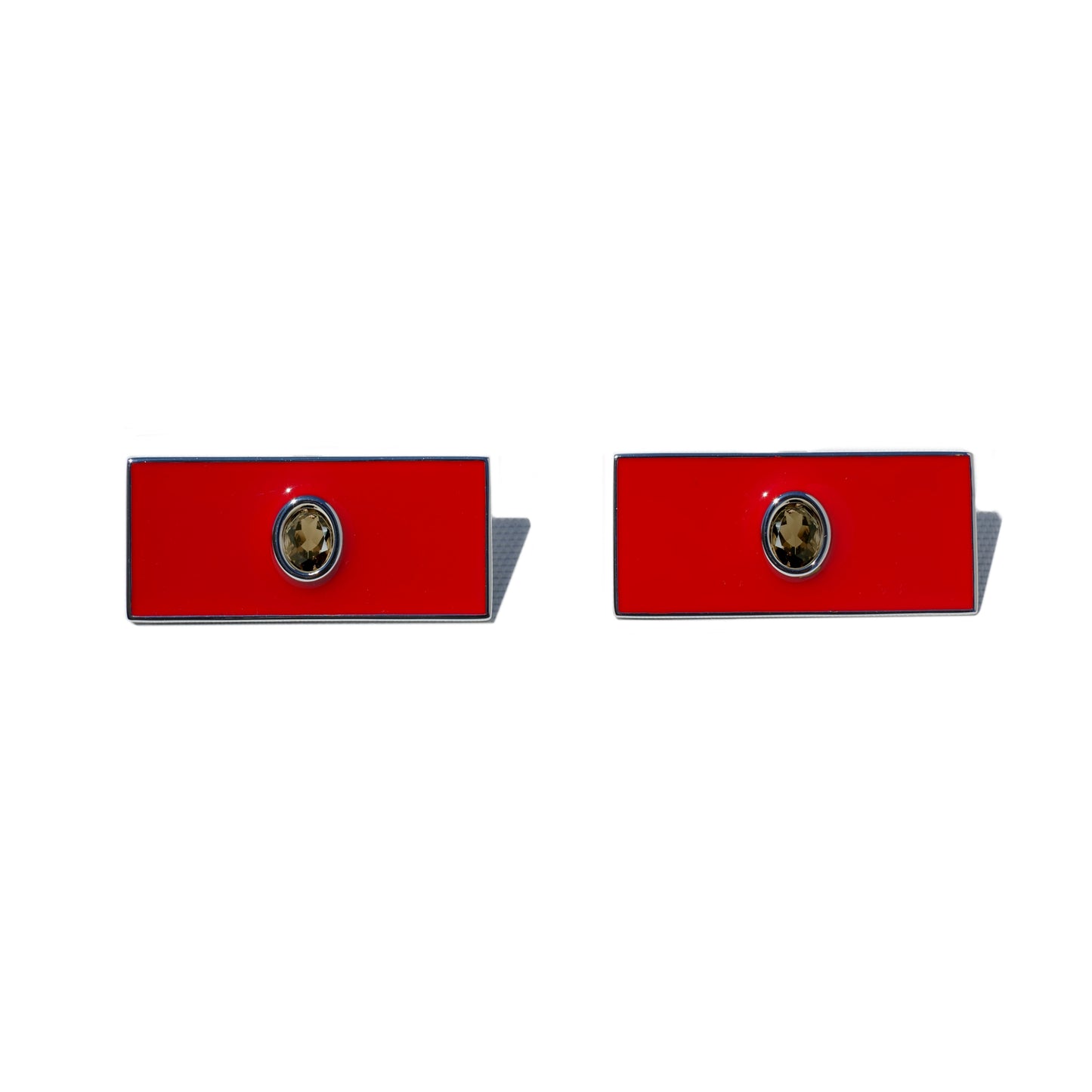 Pair of red rectangular earrings with a central emblem on a white background