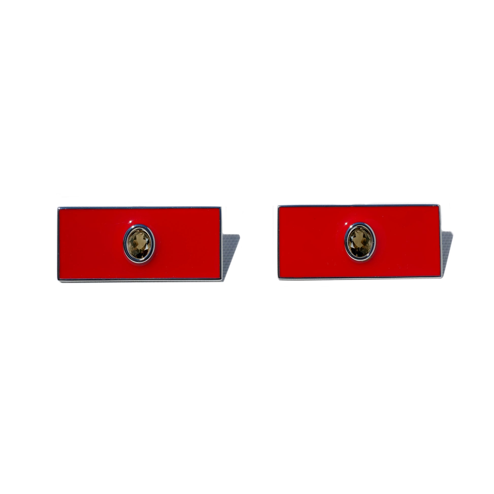 Pair of red rectangular earrings with a central emblem on a white background